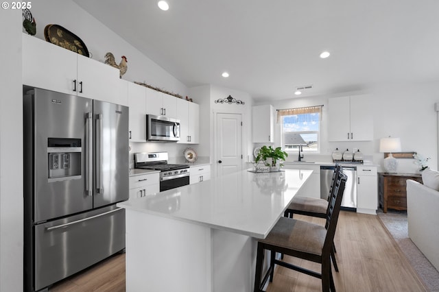 kitchen featuring white cabinets, light countertops, visible vents, a breakfast bar, and appliances with stainless steel finishes