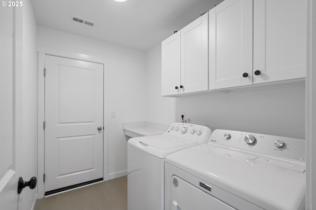 washroom featuring cabinet space, visible vents, washing machine and clothes dryer, and baseboards