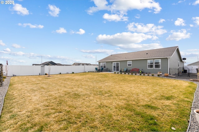 rear view of property with a fenced backyard, a gate, and a yard