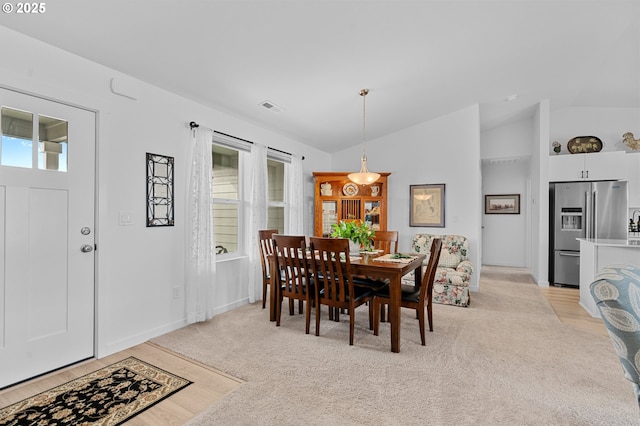 dining room with lofted ceiling, light carpet, baseboards, and visible vents