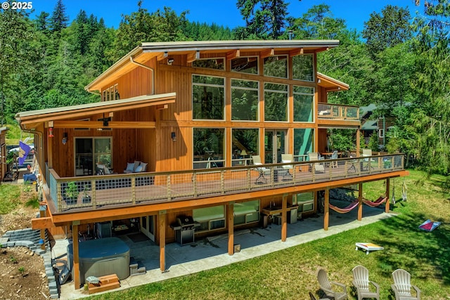 back of house featuring a ceiling fan, a patio, a wooden deck, and a hot tub