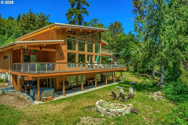 rear view of house with a patio area, a deck, a hot tub, and a yard