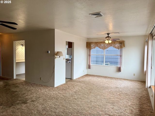 unfurnished living room with light carpet, a textured ceiling, and ceiling fan