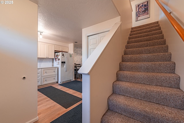 stairs featuring a textured ceiling and hardwood / wood-style floors