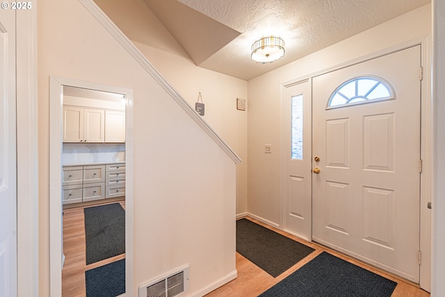 foyer entrance featuring a textured ceiling and light hardwood / wood-style floors