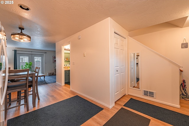 entryway featuring a textured ceiling, french doors, and light hardwood / wood-style floors