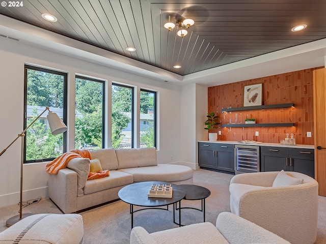 living room featuring wood walls, wooden ceiling, light carpet, bar area, and wine cooler