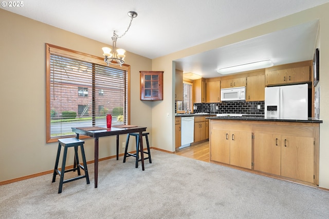 kitchen with white appliances, hanging light fixtures, backsplash, a notable chandelier, and light carpet