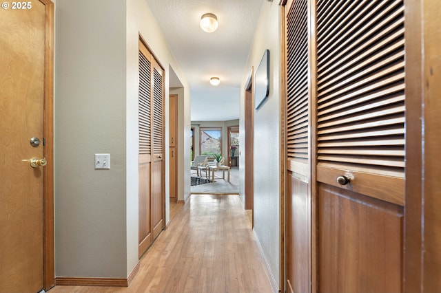 corridor featuring light hardwood / wood-style flooring and a textured ceiling