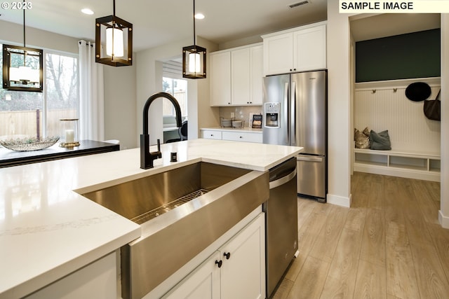 352 S 88th Ave, Ridgefield, WA 98642 - kitchen featuring stainless steel appliances, hanging light fixtures, light wood finished floors, light stone counters, and white cabinets