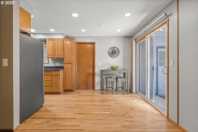 2130 SW 195th Ave, Beaverton, OR 97003 - kitchen featuring freestanding refrigerator, light wood finished floors, recessed lighting, dark countertops, and a textured ceiling