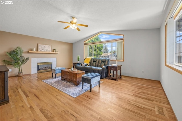 2130 SW 195th Ave, Beaverton, OR 97003 - living area with a ceiling fan, light wood-style floors, vaulted ceiling, a tile fireplace, and a textured ceiling