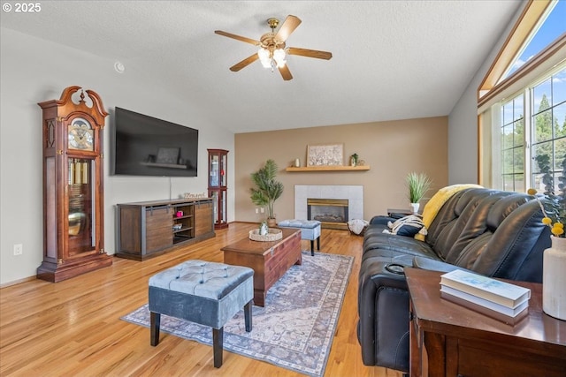 2130 SW 195th Ave, Beaverton, OR 97003 - living area with vaulted ceiling, ceiling fan, light wood finished floors, a textured ceiling, and a tiled fireplace