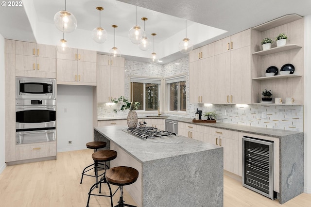 kitchen featuring a kitchen breakfast bar, appliances with stainless steel finishes, light hardwood / wood-style flooring, beverage cooler, and decorative light fixtures