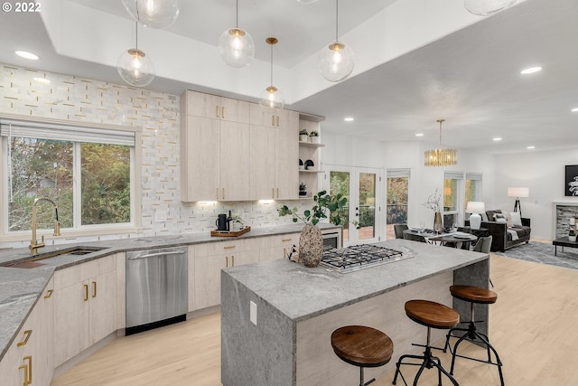 kitchen with pendant lighting, light brown cabinetry, stainless steel appliances, light hardwood / wood-style floors, and light stone countertops