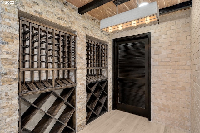 wine cellar with beamed ceiling, wood ceiling, and light wood-type flooring