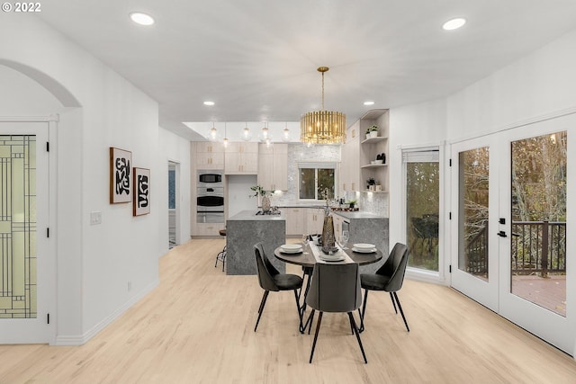 dining space featuring an inviting chandelier, light wood-type flooring, and french doors