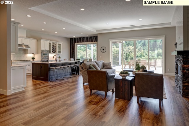 living room with plenty of natural light, wood-type flooring, and a stone fireplace