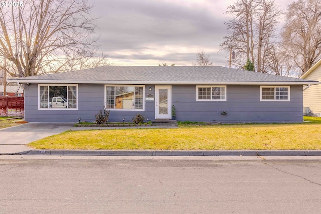 ranch-style house with roof with shingles and a front lawn