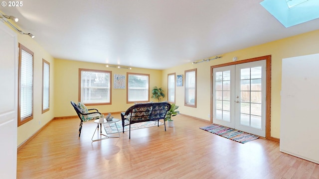 sitting room with french doors, a skylight, baseboards, and wood finished floors