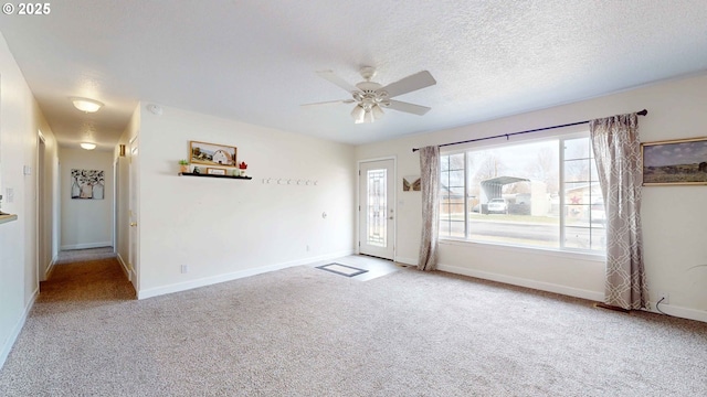 carpeted spare room with baseboards, plenty of natural light, a textured ceiling, and a ceiling fan