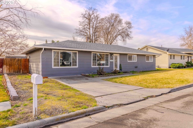 single story home featuring a shingled roof, a front lawn, and fence