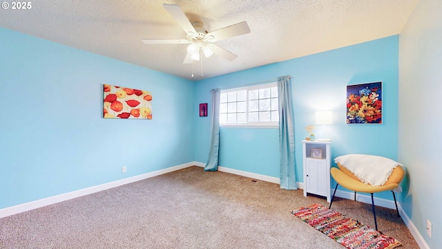 sitting room with visible vents, baseboards, ceiling fan, carpet floors, and a textured ceiling