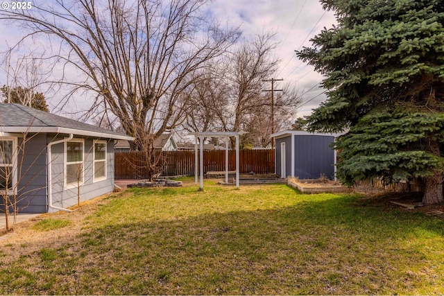 view of yard with a storage shed, an outbuilding, and fence