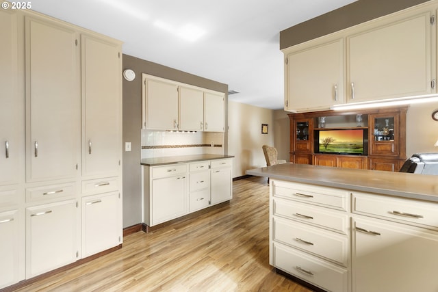 kitchen featuring light wood-style floors, tasteful backsplash, baseboards, and white cabinetry