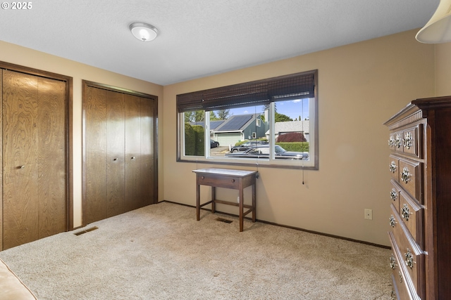 bedroom with two closets, carpet floors, and baseboards