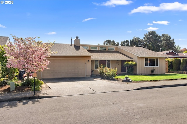 view of front of home featuring a garage, driveway, a front lawn, and a shingled roof