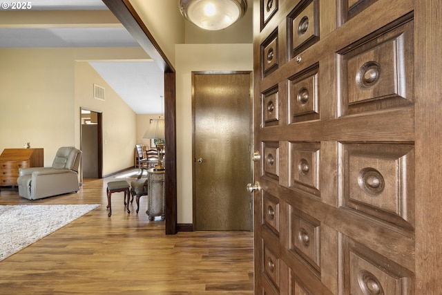 hallway featuring wood finished floors and lofted ceiling