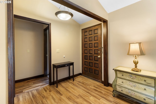 entryway featuring vaulted ceiling, light wood-style flooring, and baseboards