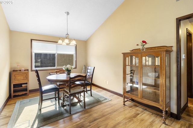 dining space with vaulted ceiling, a chandelier, light wood-type flooring, and baseboards