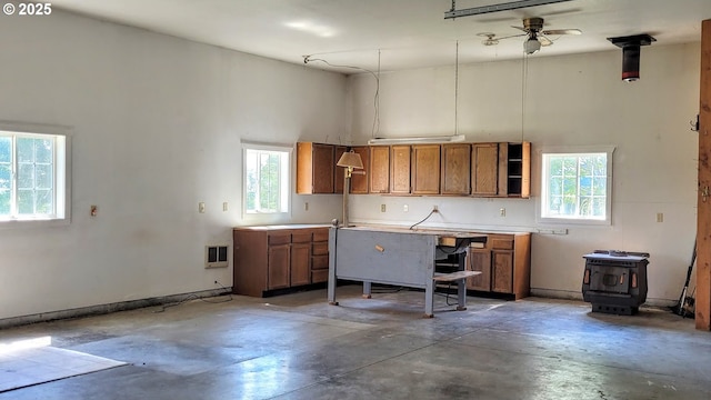 36582 Valley View Ln, Halfway, OR 97834 - kitchen featuring a wood stove, concrete flooring, a high ceiling, light countertops, and brown cabinets