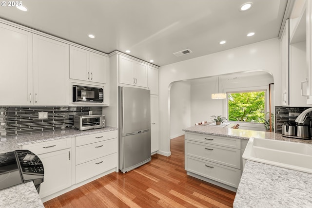 512 NE Division St, Myrtle Creek, OR 97457 - kitchen with freestanding refrigerator, arched walkways, black microwave, range, and a sink