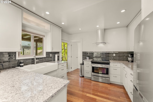 512 NE Division St, Myrtle Creek, OR 97457 - kitchen with stainless steel appliances, wall chimney range hood, a sink, tasteful backsplash, and white cabinetry