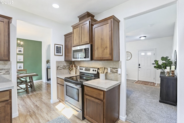 52193 SE Tussing Way, Scappoose, OR 97056 - kitchen featuring stainless steel appliances, decorative backsplash, light countertops, and arched walkways