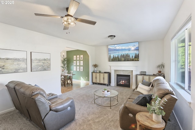 52193 SE Tussing Way, Scappoose, OR 97056 - carpeted living room featuring arched walkways, healthy amount of natural light, a lit fireplace, and a ceiling fan