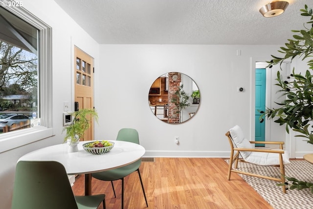 dining room featuring wood finished floors, baseboards, and a textured ceiling