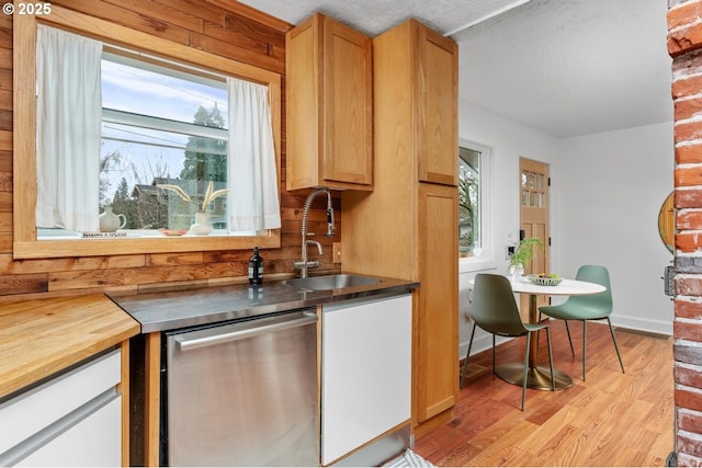 kitchen featuring dishwasher, light wood-style floors, a textured ceiling, wood counters, and a sink