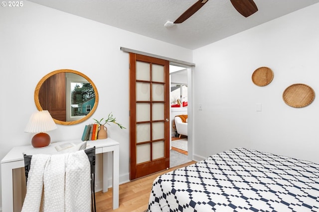 bedroom with a textured ceiling, light wood-type flooring, and ceiling fan