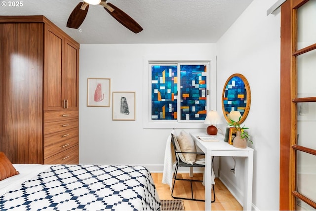 bedroom featuring light wood finished floors, baseboards, a textured ceiling, and ceiling fan