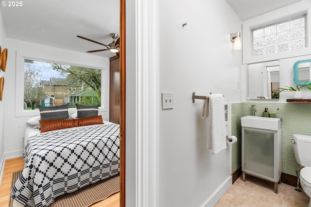 bathroom with a sink, toilet, baseboards, and ceiling fan