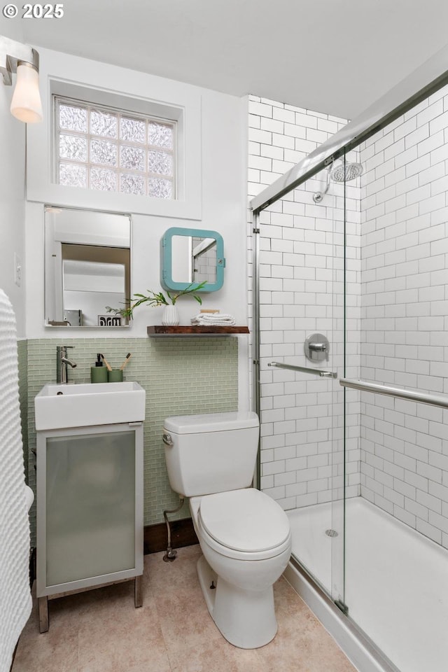 bathroom with toilet, a stall shower, tile walls, tile patterned flooring, and vanity