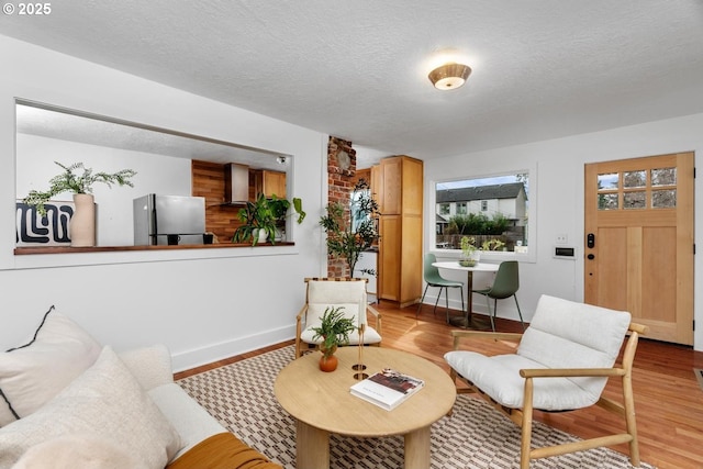 living room featuring a textured ceiling, baseboards, and wood finished floors