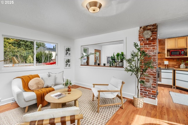 sitting room featuring light wood-style flooring, a textured ceiling, and baseboards