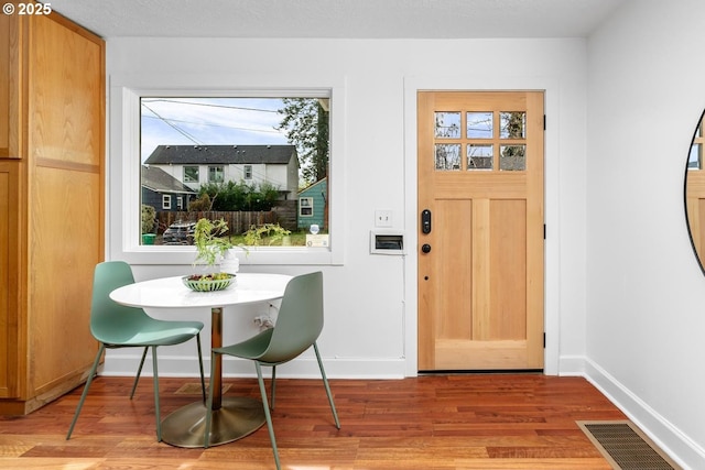 dining space featuring visible vents, baseboards, and wood finished floors