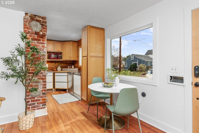 dining room featuring baseboards, a textured ceiling, and light wood finished floors