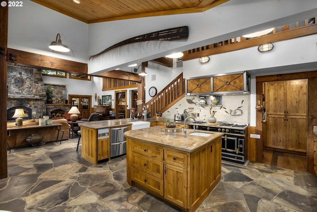 kitchen with light stone countertops, a kitchen island with sink, a fireplace, and double oven range